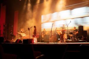 Escenario musical con músicos borrosos ensayando antes del concierto en un auditorio. foto