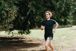 A long hair male running between the trees during a sunny day in the park with copy space photo