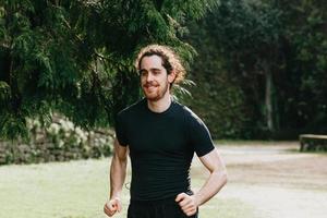 A close up of a long hair male running between the trees during a sunny day in the park photo