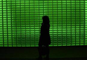 Silhouette of person standing in front of green window blinds photo
