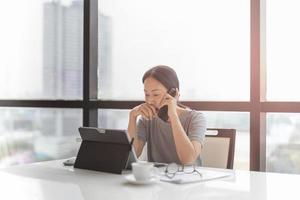 Businesswoman talking on cell phone while working on laptop photo