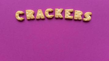 Crackers word on pink background Simple flat lay with pastel texture and copy space Stock photo