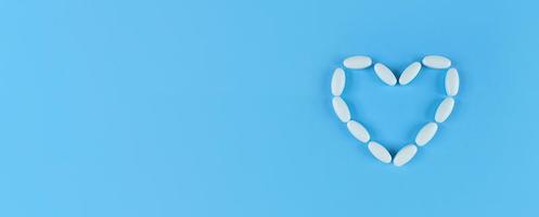 Forma de corazón hecha de tabletas blancas sobre fondo azul con espacio de copia foto