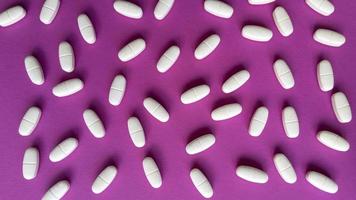 Tabletas sobre fondo rosa plano simple sentar con textura pastel concepto médico foto de stock