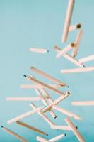 Pencils falling over a pastel blue background