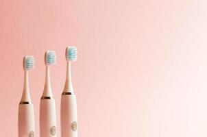 Electrical toothbrushes over a pink pastel background photo