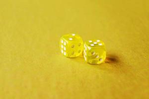 A vibrant monochromatic macro with depth of field about two yellow glass gambling dice with two numbers two and five on a yellow background photo