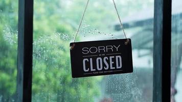 uma placa aberta pendurada na porta da frente do restaurante balançando em um dia chuvoso video