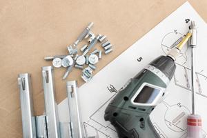 Top view of a cordless screwdriver, drawer sliders, screws and accessories for assembling furniture photo