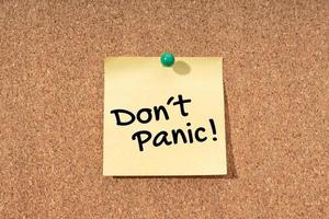 Dont panic message on yellow note on cork board photo