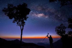 Silhouette of a Professional photographer shooting a milky way photo