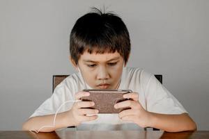 Closeup of a boy face wearing headphones and intending to play games on his smartphone photo