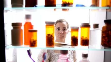 mulher procurando comprimidos no armário de remédios video