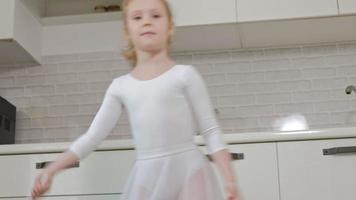 uma menina feliz em um maiô branco de ginástica treina danças com uma fita para ginástica rítmica, salta e realiza exercícios profissionais video