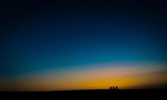 imagen de estilo de bellas artes de tres personas esperando la puesta de sol foto