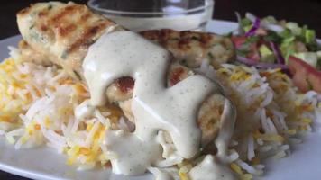 Closeup photography of chicken kebab with white sauce and fried rice served on white plate
