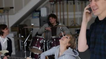 Young man in garage with band talking on cell phone video