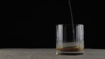 Whiskey is poured into a glass in dark room video