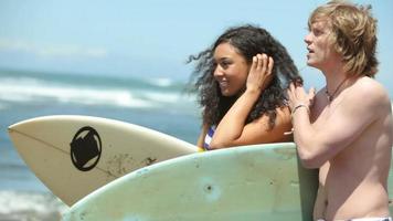 Portrait of couple at beach with surfboards