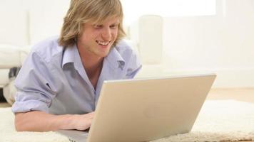 Young man laying on floor with laptop computer video