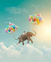 Niña montando un elefante con globos volando en el cielo concepto de logro de metáfora de fantasía