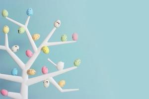 Pequeño árbol decorativo con coloridos huevos de codorniz en las ramas de fondo de Pascua con espacio de copia