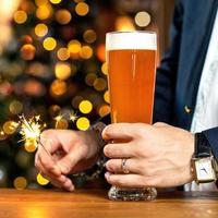 Traje con hombre sosteniendo un vaso de cerveza y bengalas encendidas foto