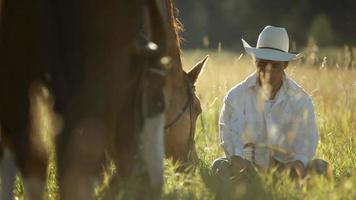 Cowboy sitzt im Gras und macht Pause mit Pferden video