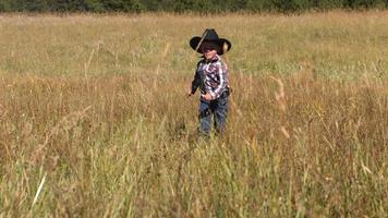 Young cowboy runs in grassy field, slow motion video