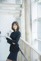 Attractive asian business woman working on tablet computer outside Office photo