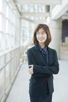 Atractiva mujer de negocios asiática sonriendo fuera de la oficina foto