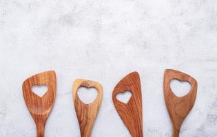 Varias en forma de corazón de utensilios de cocina de madera cucharas de madera y espátula de madera sobre fondo de hormigón con espacio plano y copia foto