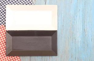 Black and white plate on tablecloth on wood table background photo