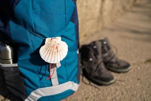 Close-up of a seashell, symbol of Camino de Santiago on backpack and trekking boots photo