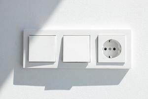 Tablero de interruptores blanco moderno con dos interruptores y un enchufe europeo foto