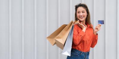 Retrato al aire libre de mujer feliz sosteniendo bolsas de compras con tarjeta de crédito