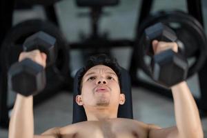 Sporty man training with dumbbell in gym