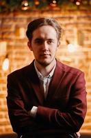 Serious man in vinous suit with christmas background behind photo