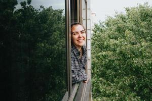 Mujer sonriendo a la ventana durante un día de primavera foto