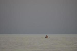 pescadores en un bote de remos en el mar al atardecer foto