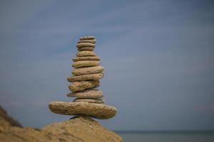 balancing pyramid of stones on a large stone on the seashore photo