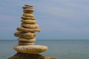 balancing pyramid of stones on a large stone on the seashore photo