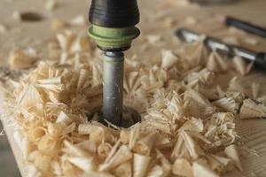 The joiner drills a workpiece of wood with a drill photo