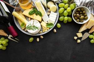 Various types of cheese, grapes, wine and snacks photo