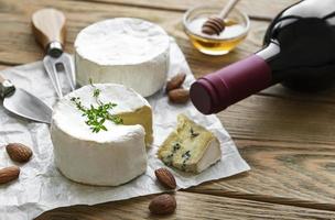 Various types of cheese, blue cheese, bree, camembert, and wine on a wooden table photo