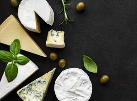 Various types of cheese on a black concrete background photo