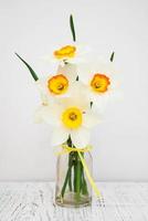 Daffodils in a vase on an old wooden background photo