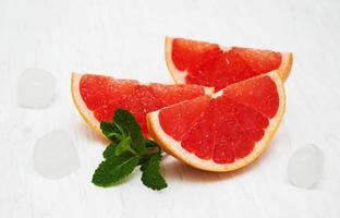 Grapefruit with mint and ice on an old white wooden background photo