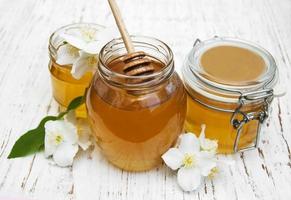 Honey with jasmine flowers on a wooden background