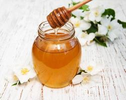 Honey with jasmine flowers on a wooden background